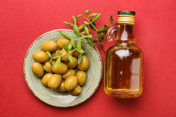 Bottle of oil with olives on color background