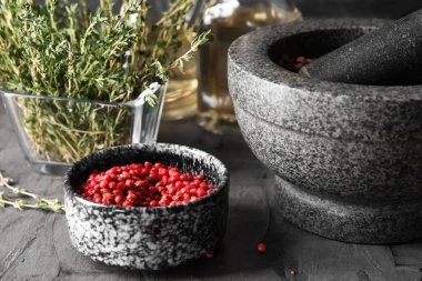 Pembe biber, harç ve gri masada kekik ile kase