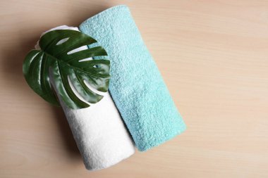 Ahşap arka plan üzerinde temiz yumuşak havlu tropikal yaprak ile haddelenmiş