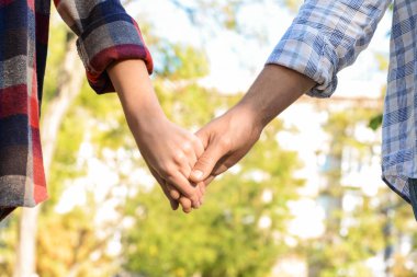 Dışarıda el ele tutuşan genç bir çift.