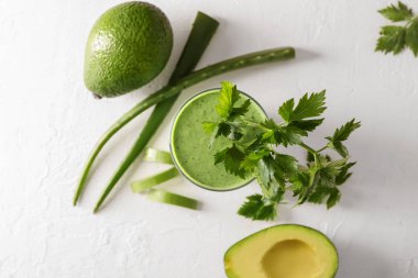 Sağlıklı aloe maydanoz ve kesim beyaz masaya avokado ile kokteyl bardak