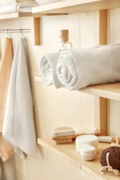 Clean soft towels with cosmetic products on shelves in bathroom