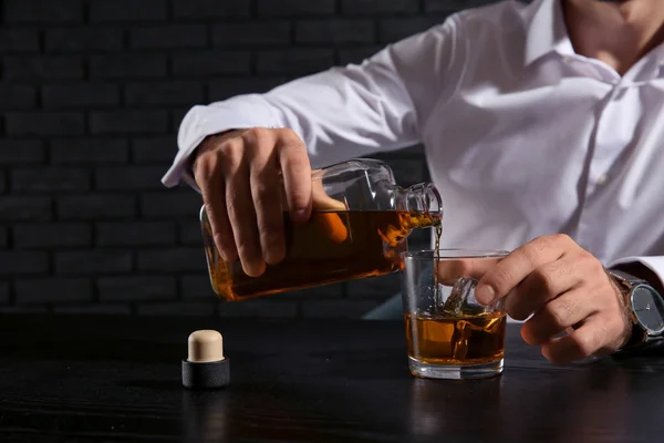 Uomo Versare Whisky Vetro Mentre Seduto Tavola Sfondo Scuro — Foto Stock