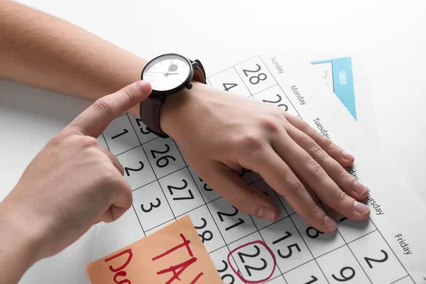 ライト テーブルの彼女の時計とカレンダーを探している女性 期限の概念 — ストック写真