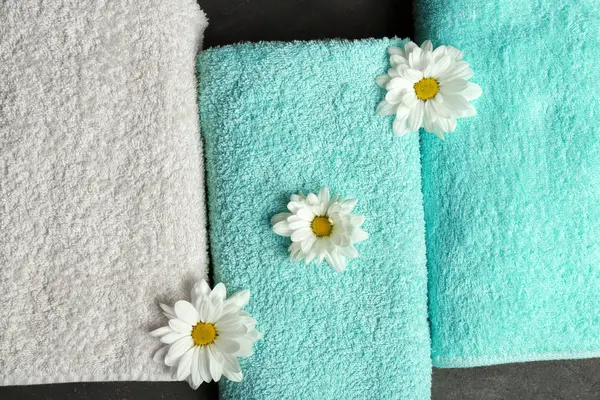 Clean soft towels with flowers on grey background