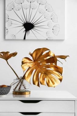 Komodin ışık duvarının yakınında altın tropikal yaprak