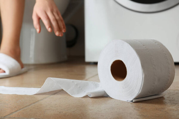 Woman making long arm for toilet paper on floor of restroom