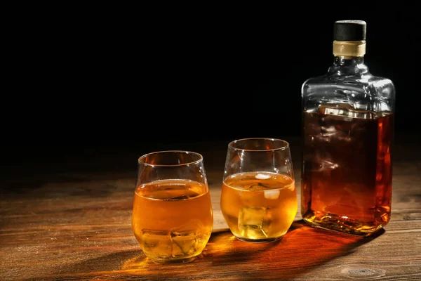 ボトル 暗い背景に木製のテーブルにウィスキーのグラス — ストック写真