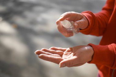 Açık havada, antibakteriyel el dezenfektanı kullanan kadın portre