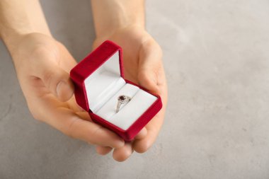Nişan yüzüğü gri arka plan üzerinde kutusuyla holding erkek eller