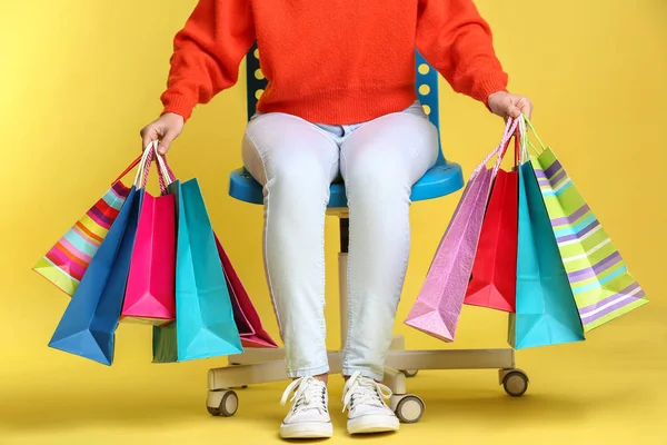 Mooie Jonge Vrouw Met Boodschappentassen Zit Stoel Tegen Een Achtergrond — Stockfoto