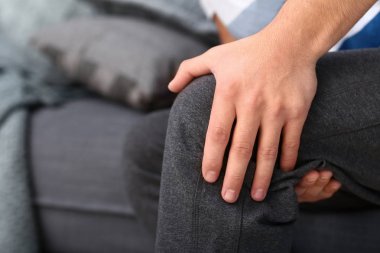 Genç adam closeup evde, bacak ağrısı muzdarip