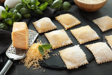 Pişmemiş ravioli karanlık masada rendelenmiş peynir ile