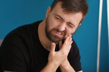 Evde diş ağrısı çeken bir adam.