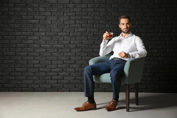 Joven Hombre Negocios Bebiendo Whisky Cerca Pared Ladrillo Oscuro —  Fotos de Stock