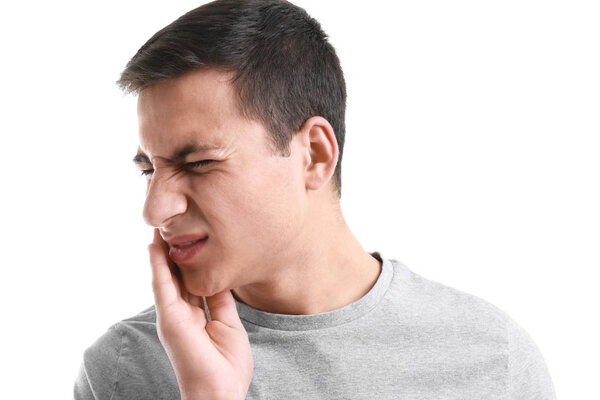 Young man suffering from toothache on white background