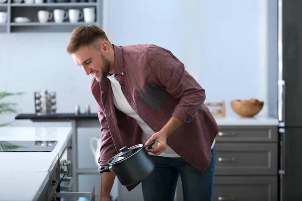 Ung Man Sätta Kastrullen Skåpet Vid Rengöring Kök — Stockfoto