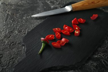 Red hot chili peppers ve gri dokulu arka plan üzerinde bıçak ile kesme tahtası