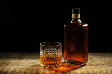 Şişe ve bardak viski koyu arka plan karşı ahşap tablo