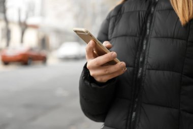 Dışarıda cep telefonu kullanan genç bir kadın.