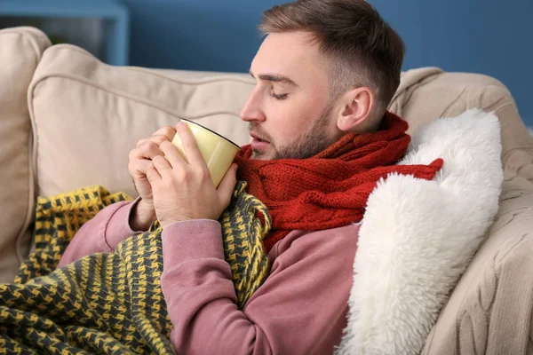 Young man ill with flu drinking hot tea at home