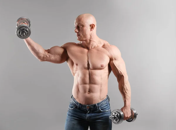 Muskulöser Bodybuilder Mit Kurzhanteln Auf Grauem Hintergrund — Stockfoto