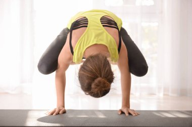Evde yoga yapan genç bir kadın.
