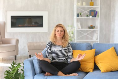Evinde meditasyon yapan güzel genç bir kadın.