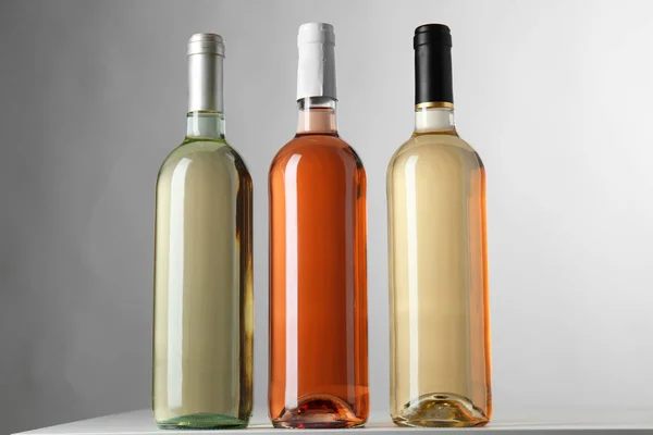 瓶与不同种类的酒在灰色背景 — 图库照片