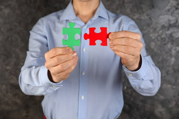 Man with pieces of color puzzle on grey background