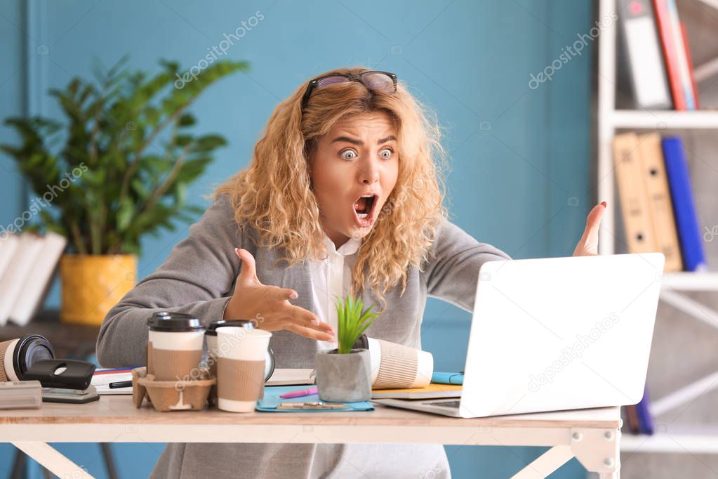 Stressed young businesswoman at table in office