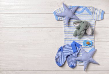 Bebek giysileri ayarla ve aksesuarları düz beyaz ahşap zemin üzerinde yatıyordu