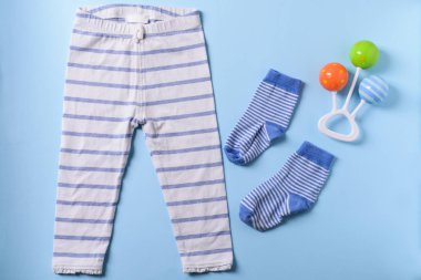 Bebek giysileri ve rattle renk arka plan üzerinde düz yatıyordu
