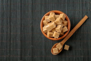 Kase ve kaşığı kahverengi şeker kamışı karanlık tablo ile