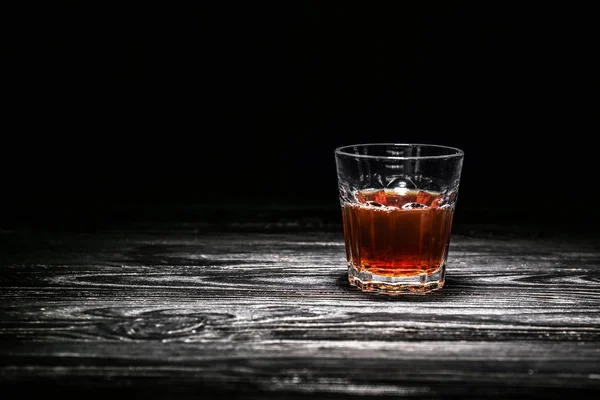 黒の背景に木製のテーブルの上の氷を入れたウイスキーのガラス — ストック写真