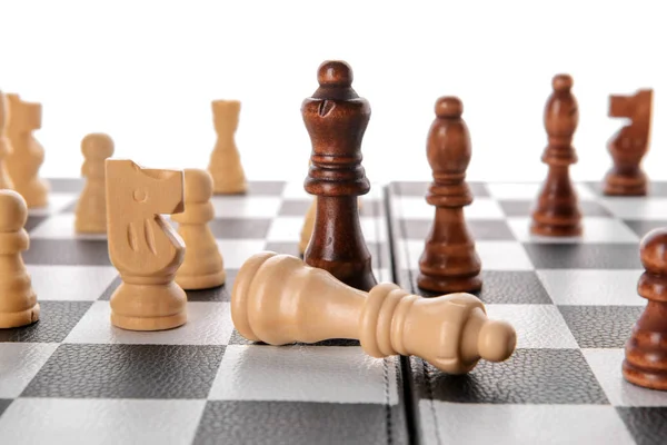 Chess pieces on game board against white background, closeup