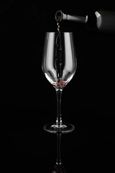 在黑暗背景下将红酒从瓶子倒入玻璃杯 — 图库照片