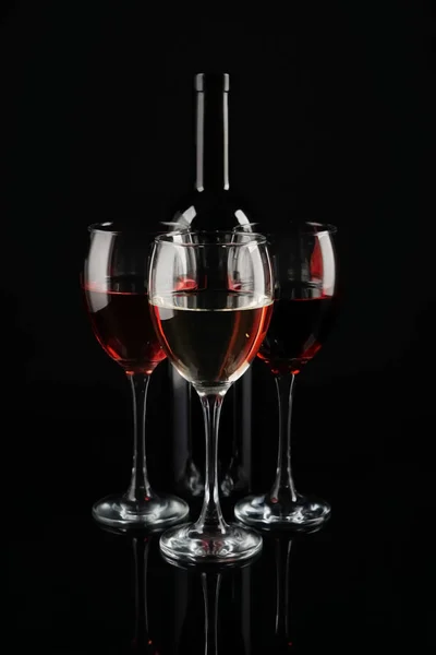 Bottle and glasses of red wine on dark background