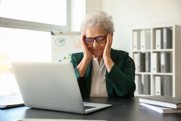 在室内使用笔记本电脑时头痛的老年妇女 — 图库照片