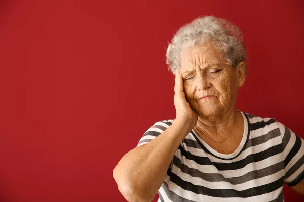 色の背景で頭痛に苦しんでいるシニア女性 — ストック写真