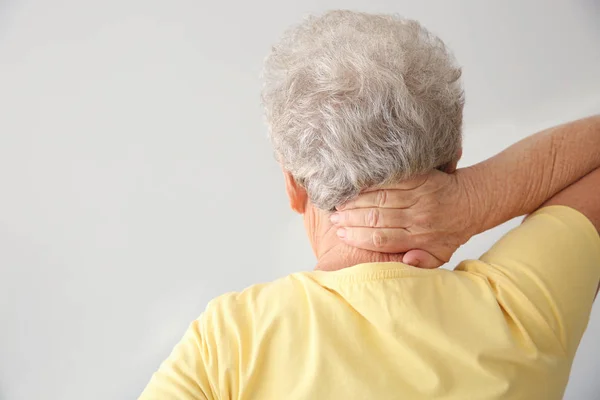 Seniorin Leidet Nackenschmerzen Vor Hellem Hintergrund — Stockfoto