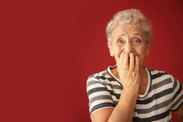 Portrait of elderly woman after making mistake on color background