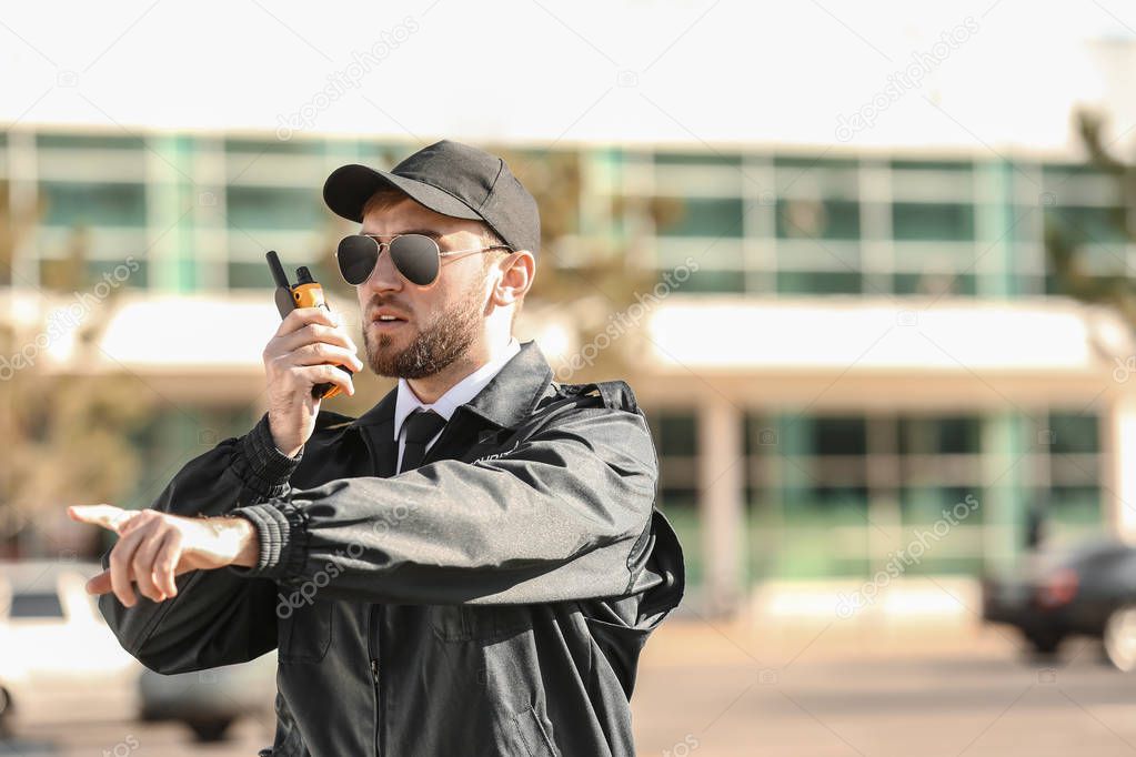 Male security guard with portable radio transmitter outdoors