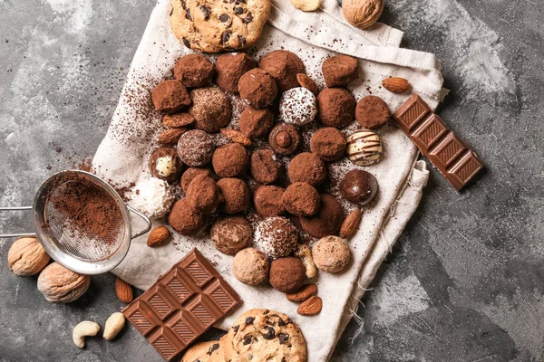 Tasty chocolate truffles with nuts and cookies on grey table