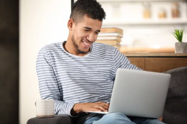 Afrikalı-Amerikalı genç adam evde laptop ile çalışma