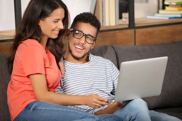 自宅のソファに座ってノート パソコンを持つ若いカップルします — ストック写真
