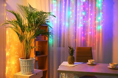 Decorative Areca palm in room near window with fairy lights clipart