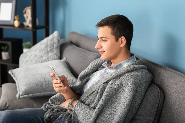 Handsome young man with mobile phone resting at home