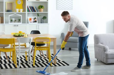 Genç adam dairesini temizliyor.