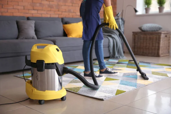 Female janitor hoovering carpet in flat